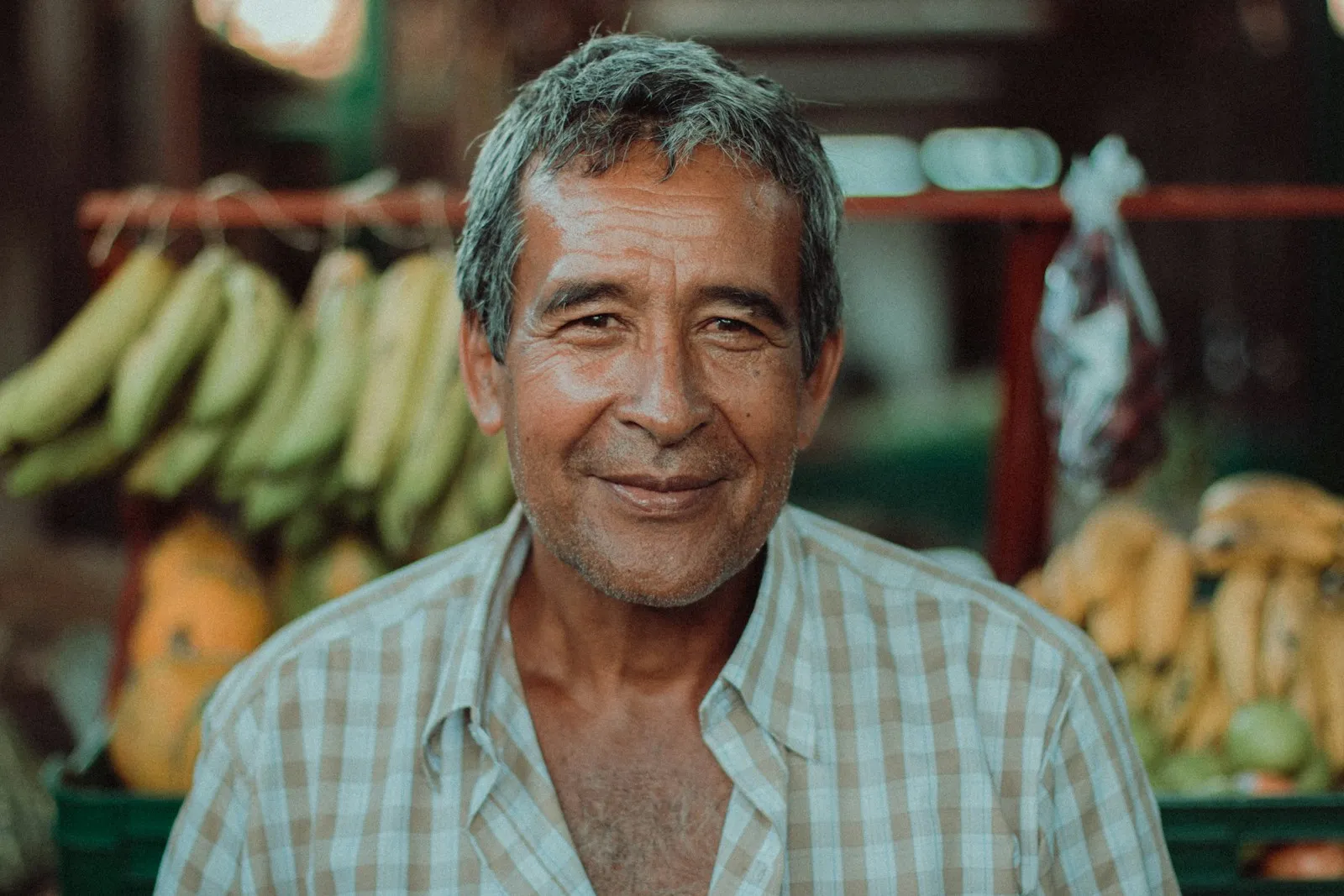 Feirante sorrindo na frente da banca de frutas